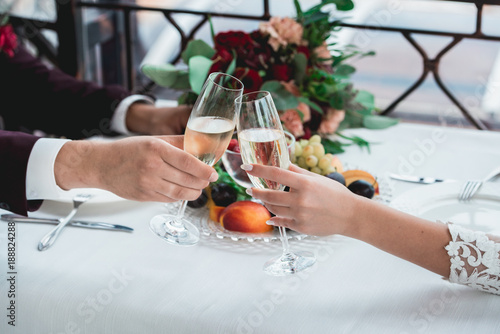 Glasses with champagne drink in bride and groom hands. Happy newlyweds drinking. Loving couple created new family. photo
