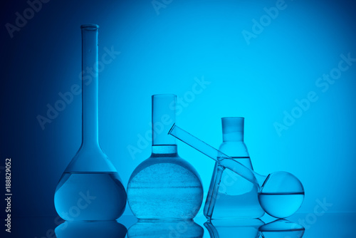 different glass flasks with liquid for chemical test on blue
