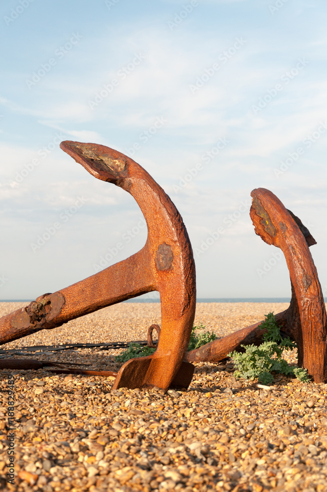 Fototapeta premium Two old, rusted anchors lying on a pebble beach in England
