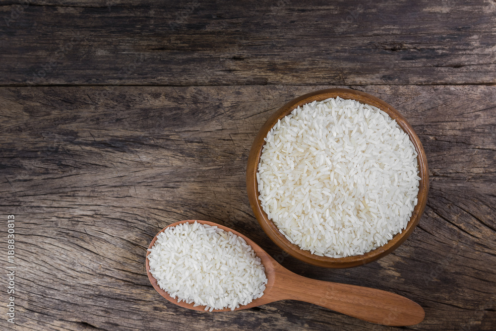 top view of raw dry Thai jasmine rice seeds in a bowl on old and crack wooden board with copy space for text. top view of raw dry Thai jasmine rice seeds in a bowl on old and crack wooden board with copy space for text.