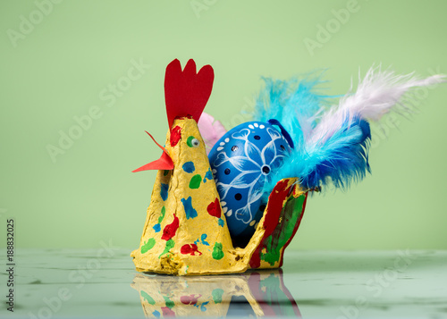 Closeup of a colorful handicraft chicken with a blue easter egg