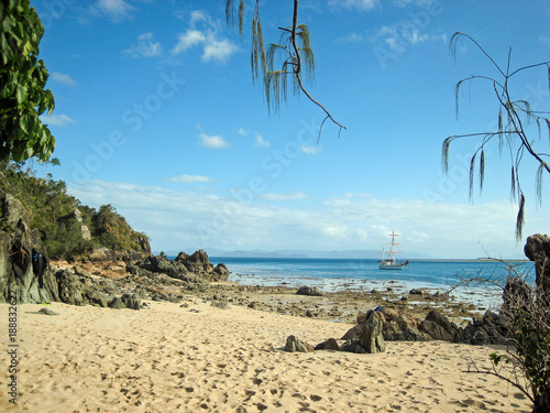A secluded bay on the Great Barrier Reef with a single sailing ship off shore