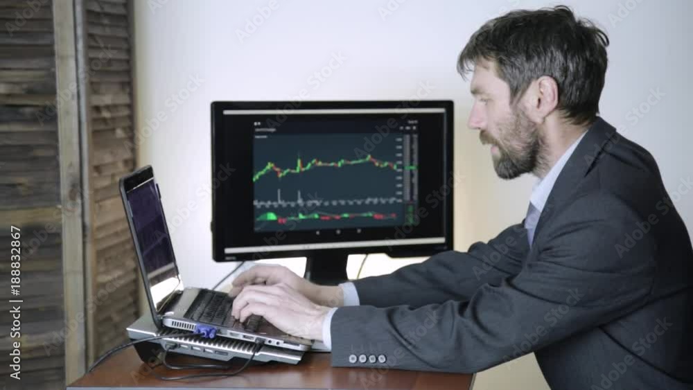 trader watching changes in the currency exchange chart, looking at laptop. Work on a stock exchange. trader watching changes in the currency exchange chart, looking at laptop. Work on a stock exchange.