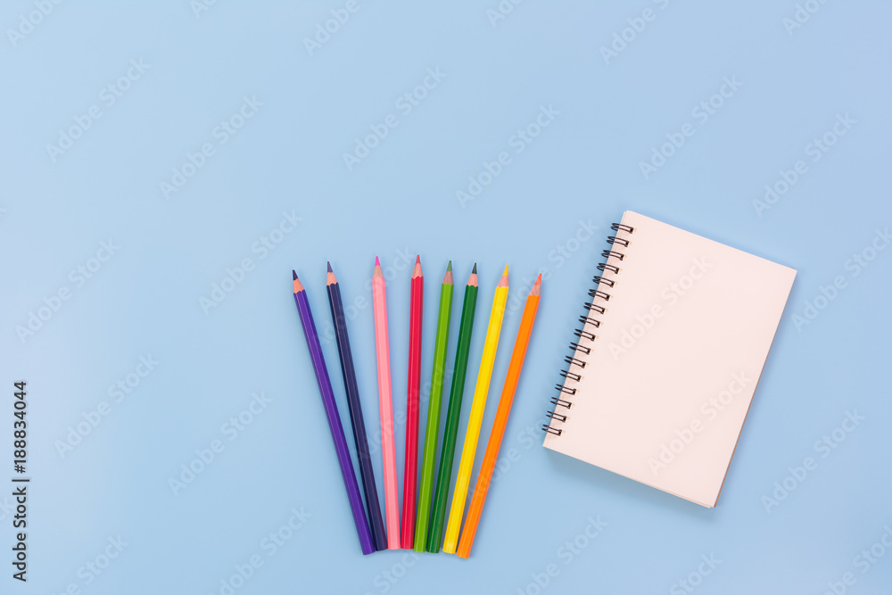 Fototapeta premium top view of blank notebook and coloured pencils on light blue background with copy space. memo and planning concept.