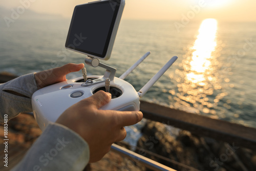 silhouette of remote control a flying drone which taking photo over sunrise sea
