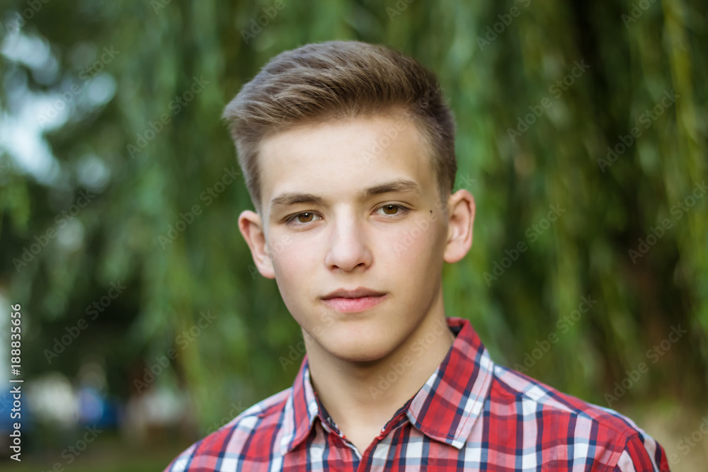 Portrait of a teenager close-up. The young guy. Teenager in a red checkered shirt. Portrait of a teenager close-up. The young guy. Teenager in a red checkered shirt.