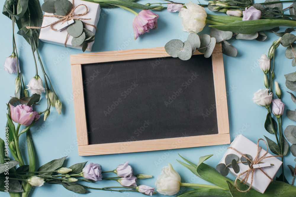 Fototapeta Skład dzień matki: Eustoma, eukaliptus, tulipany, tablica z miejsca na kopię i pudełka na niebieskim tle. Top view.Llat lay.
