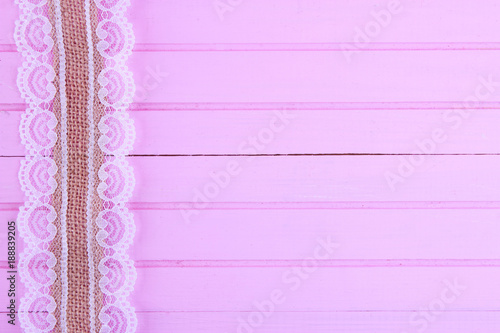 Burlap lace on pink wooden background