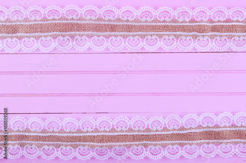 Burlap lace on pink wooden background