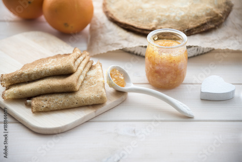 pancakes and orange jam on a light wooden background