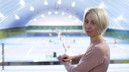 Young blonde observes after tennis players from baclony at the court photo