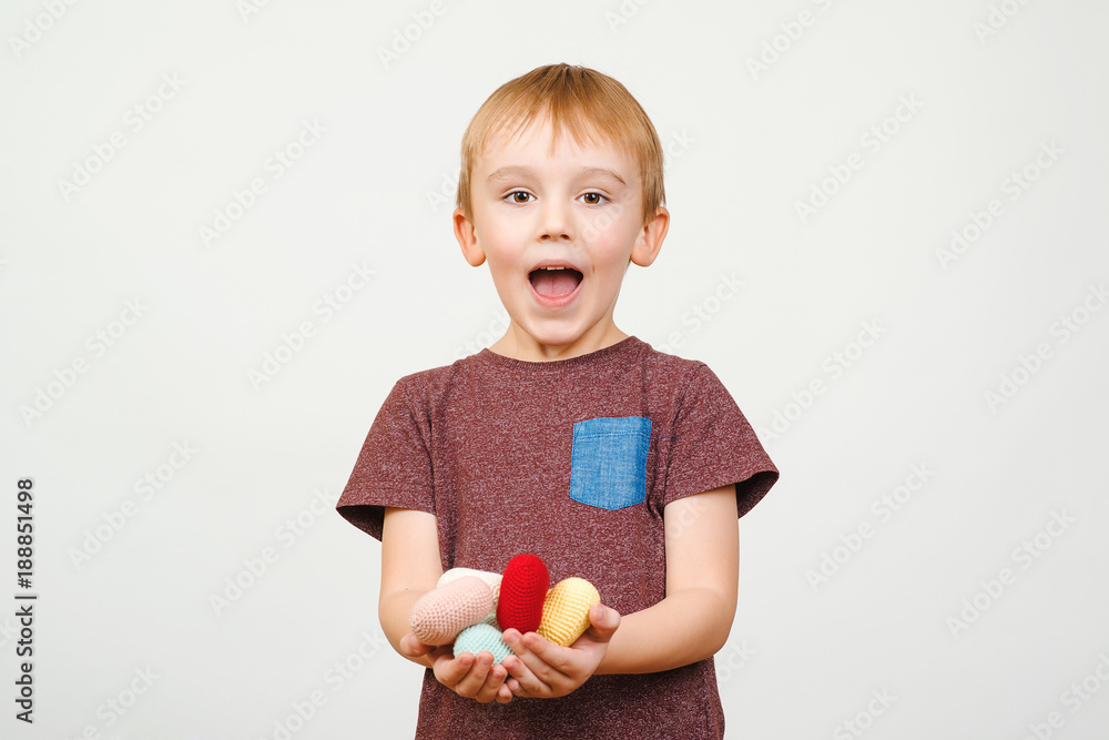 Happy cute boy holds a lot of colored knitted hearts, isolated on white background. Happy cute boy holds a lot of colored knitted hearts, isolated on white background.