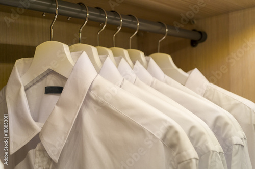 A row of symmetrically hung white mens shirts