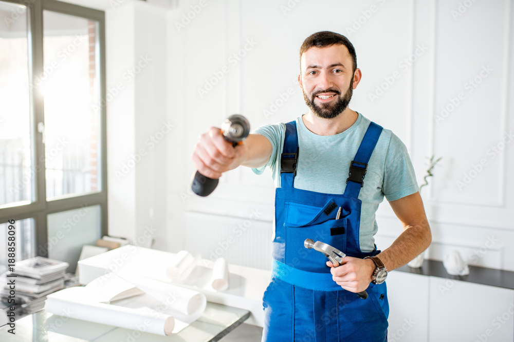 Portrait of a handsome repairman in workwear standing with screwdriver in the office Portrait of a handsome repairman in workwear standing with screwdriver in the office