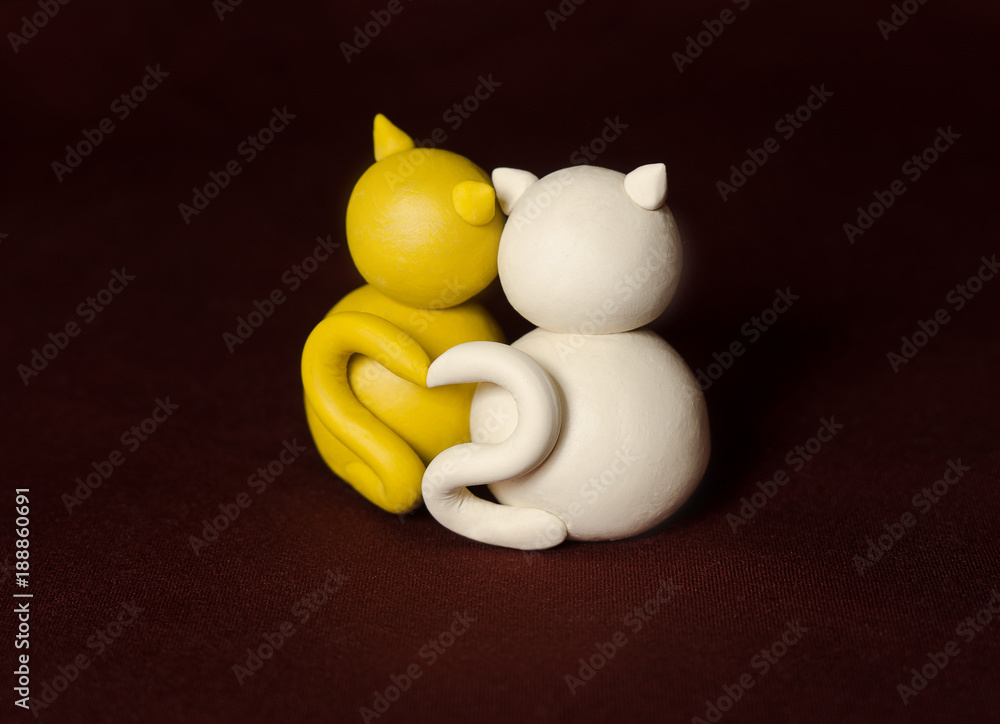 Two minimalistic animal figures in love. Lovely cat plasticine models having tails in heart shape isolated on dark red background. Happy Valentine's Day in minimalism style.