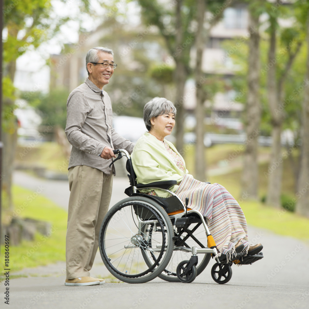 車椅子で散歩をするシニア夫婦 車椅子で散歩をするシニア夫婦