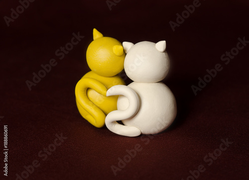 Obraz na płótnie Two minimalistic animal figures in love. Lovely cat plasticine models having tails in heart shape isolated on dark red background. Happy Valentine's Day in minimalism style. w salonie