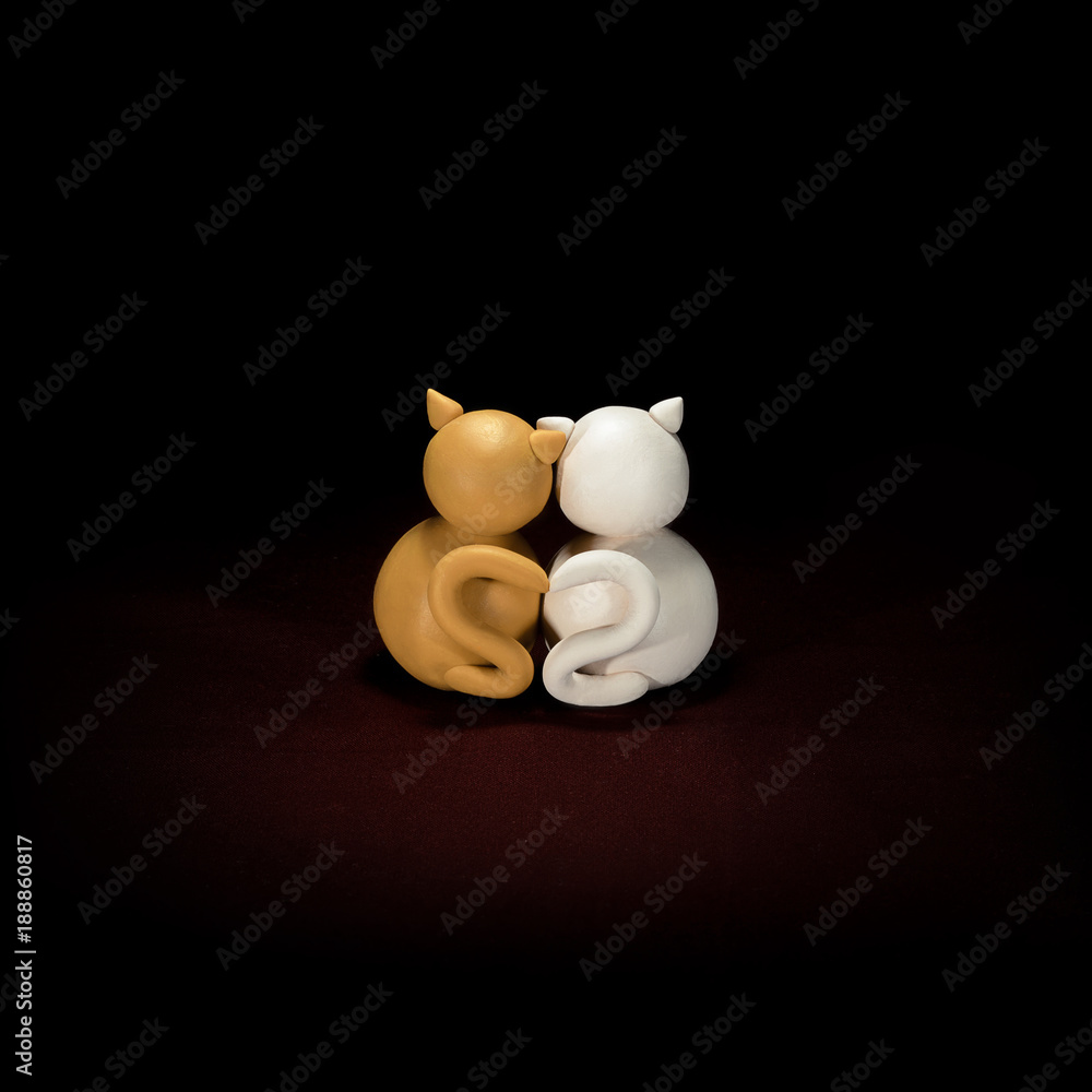 Two minimalistic animal figures in love. Lovely cat plasticine models having tails in heart shape isolated on dark red background. Happy Valentine's Day in minimalism style.
