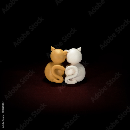 Obraz na płótnie Two minimalistic animal figures in love. Lovely cat plasticine models having tails in heart shape isolated on dark red background. Happy Valentine's Day in minimalism style. w salonie