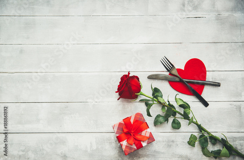 Valentine's day table setting with fork, knife, red hearts, ribbon and roses. Valentines day background or first date