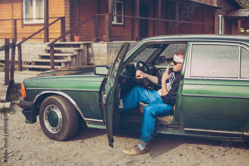 guy in the nineties sits behind the wheel of a car Smoking a cigarette