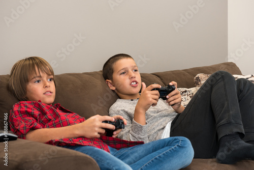 Two happy  young boy friends playing video games, holding remote controlers photo