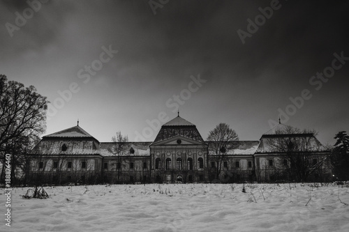 Medieval snowy castle in winter at night with beautiful orange - red sky. Creepy castle in Slovakia. European historic large castle in park.