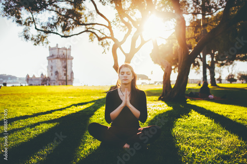 Carefree happy woman practicing yoga and meditation in lotus pose near Torre de Belem.Mindfulness and daydreaming.Enjoying in Lisbon.Sunset in Portugal photo