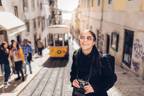 Young cheerful woman walking down the street of Lisbon.Amazed tourist visiting Europe off season during winter.Student in Portugal,Europe on a spring brake trip exploring big cities.Positive female