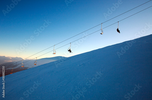 Ski lift in winter snowy landscape in mountains on blue sky background