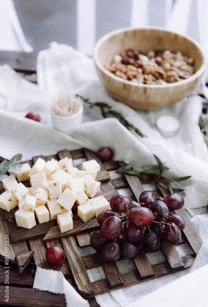 A beautifully served table with grapes, cheese, nuts and greens on a tree and napkins in rustic style