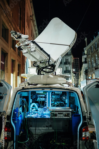 Opened door of parked satellite TV van transmitting breaking news events to satellites for broadcast around the world at night in city