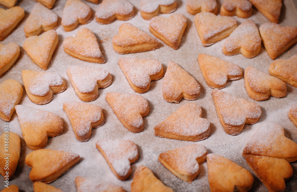 cookies in the form of hearts in powdered sugar lies on parchment paper