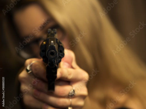 A girl with white hair and a gun in her hands is aiming at the camera, self-defense, attack, weapons. selective focus