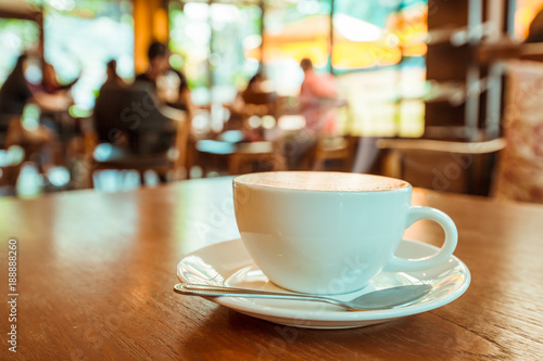 Cup of hot coffee on table in cafe with people. vintage and retro color effect - shallow depth of field