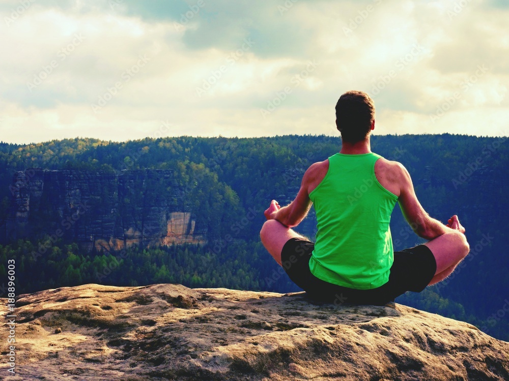 Man on top of mountain in yoga pose. Exercise yoga on edge with a breathtaking view Man on top of mountain in yoga pose. Exercise yoga on edge with a breathtaking view