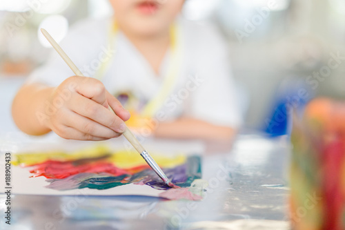 Portrait of adorable little asian girl holding a paintbrush and working on a painting for art class in school.Confidence Positivity Freedom Be Creative Concept.