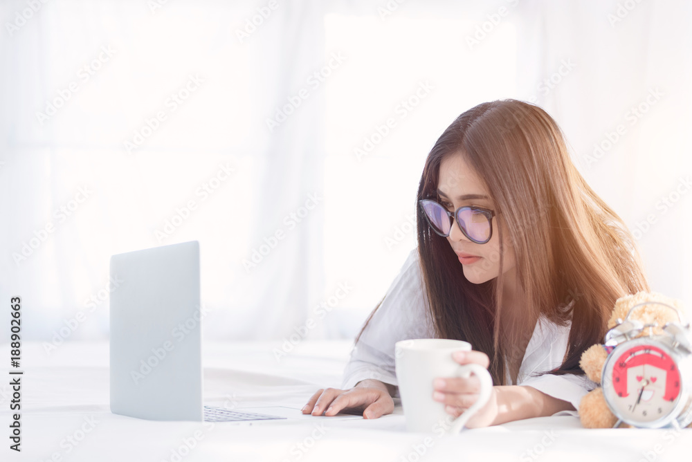 Portrait of a young business woman ,laptop,cup of coffee. Business concept a laptop drinking coffee with her computer on the bed Portrait of a young business woman ,laptop,cup of coffee. Business concept a laptop drinking coffee with her computer on the bed