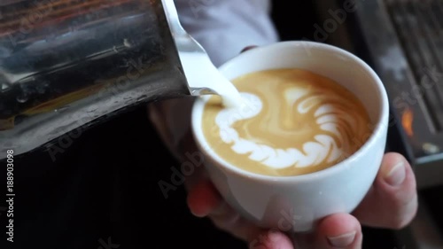 Barista pouring milk in cappuccino and doing latte art in coffee shop. photo