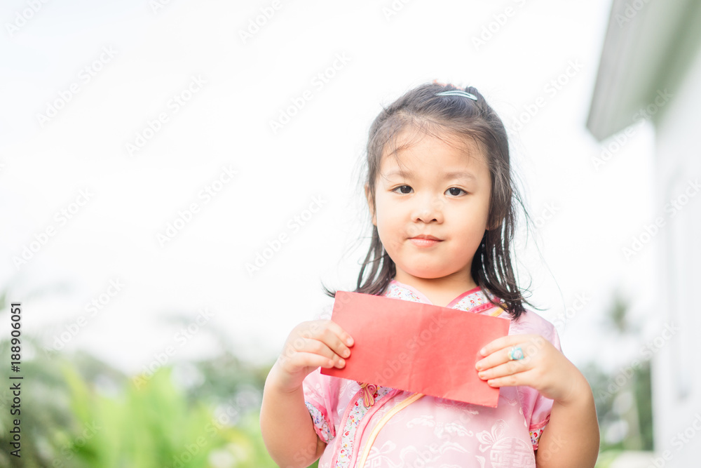 Happy Little asian girl in chinese traditional dress smiling and holding red envelope.Happy chinese new year concept. Happy Little asian girl in chinese traditional dress smiling and holding red envelope.Happy chinese new year concept.