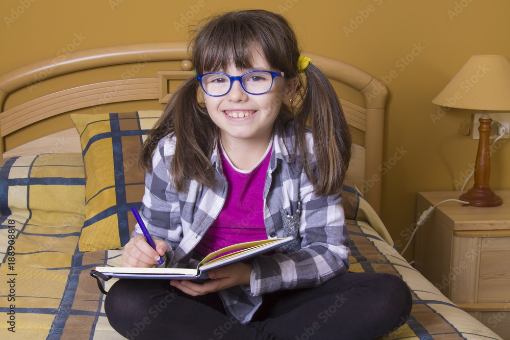 little girl writing in the notebook with colored pencils little girl writing in the notebook with colored pencils