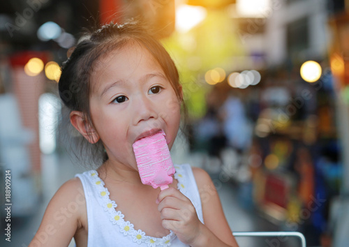 Little asian child girl eating ice-cream.