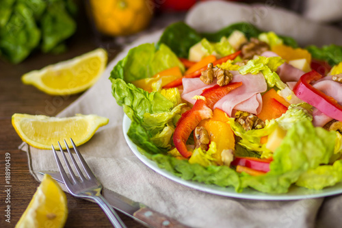 bowl of fresh salad with vegetables and greens on wooden table