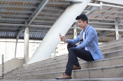 Young businessman holding a phone in downtown.