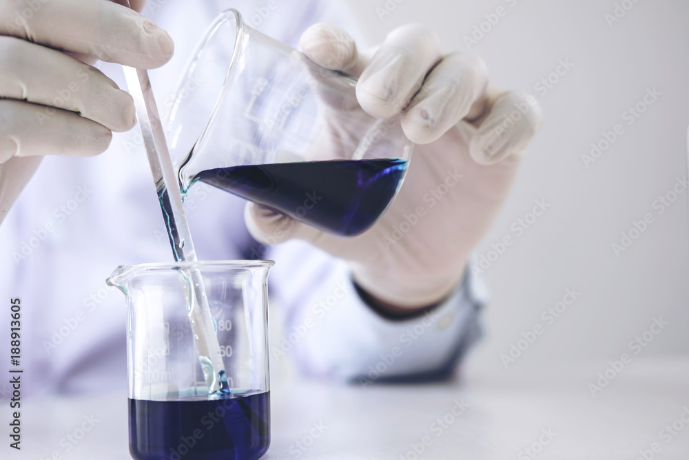 Scientist or medical in lab coat working in biotechnological laboratory equipment for research with mixing reagents in glass flask in clinical laboratory Scientist or medical in lab coat working in biotechnological laboratory equipment for research with mixing reagents in glass flask in clinical laboratory