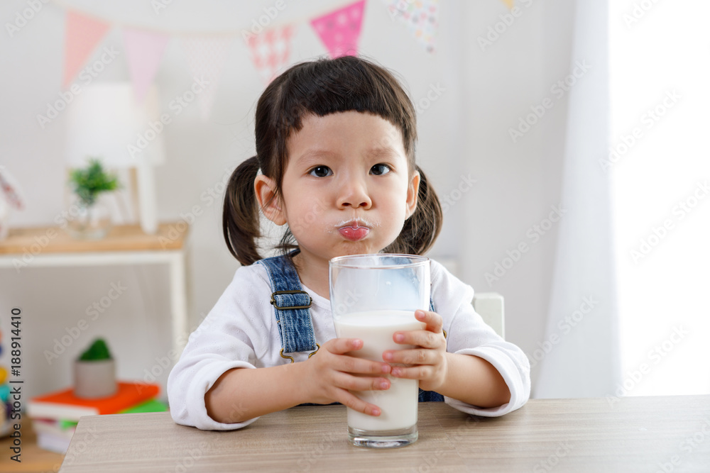 Adorable baby girl with dringking milk with milk mustache holding glass of milk Adorable baby girl with dringking milk with milk mustache holding glass of milk