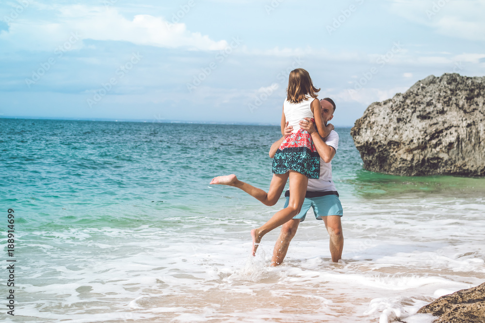 Happy young honeymoon couple having fun on the beach. Ocean, tropical vacation on Bali island, Indonesia. Happy young honeymoon couple having fun on the beach. Ocean, tropical vacation on Bali island, Indonesia.