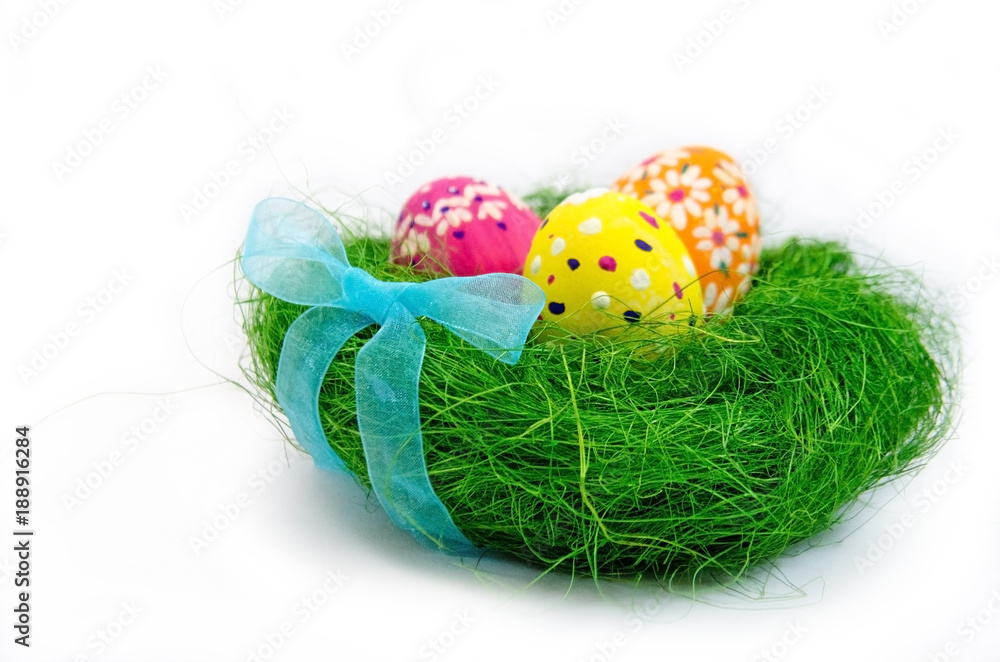 Easter eggs in nest from grass with a bow on white background