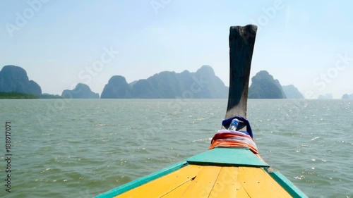 Thai Thaditional longtail boat sails on the waves toward the amasing mountains photo