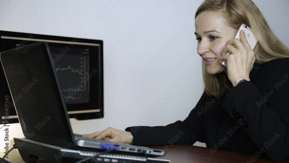 Business lady advises client on a phone and watching currency exchange chart at the computer monitor. Work on a crypto stock exchange Business lady advises client on a phone and watching currency exchange chart at the computer monitor. Work on a crypto stock exchange